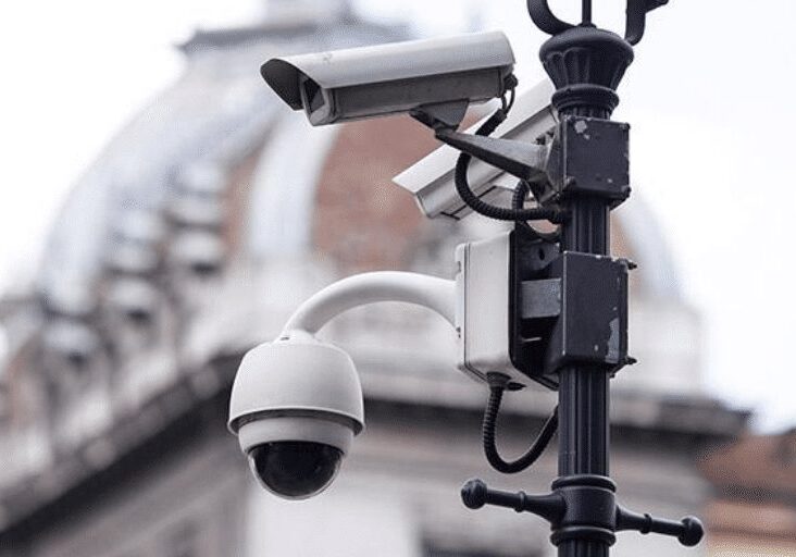 An assortment of video surveillance cameras mounted on light post net to a building